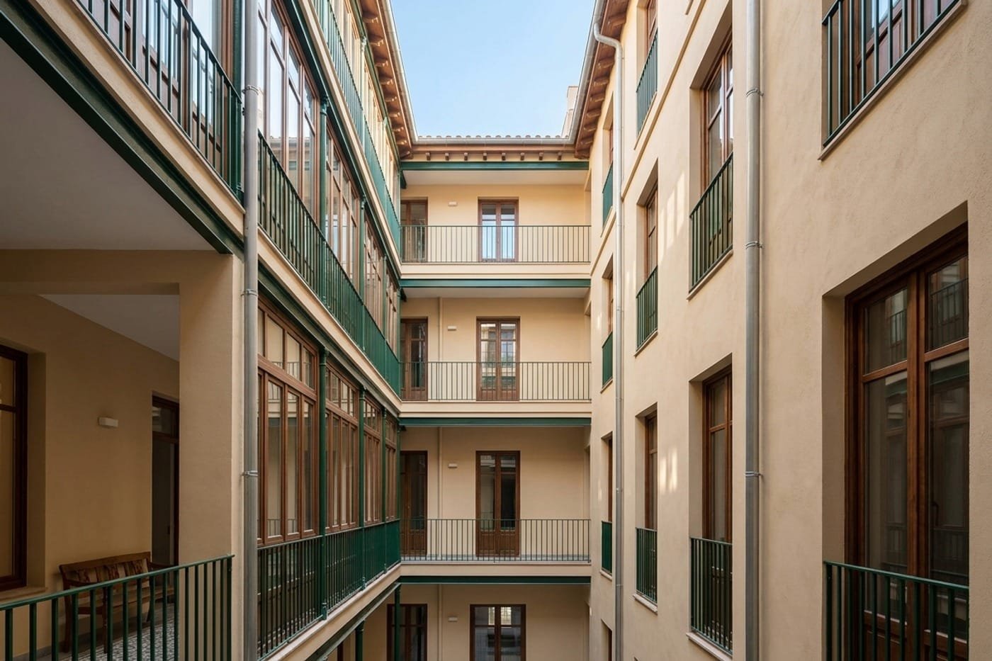Patio interior de una finca de Barcelona con la fachada recién pintada en un tono claro y las barandillas esmaltadas.