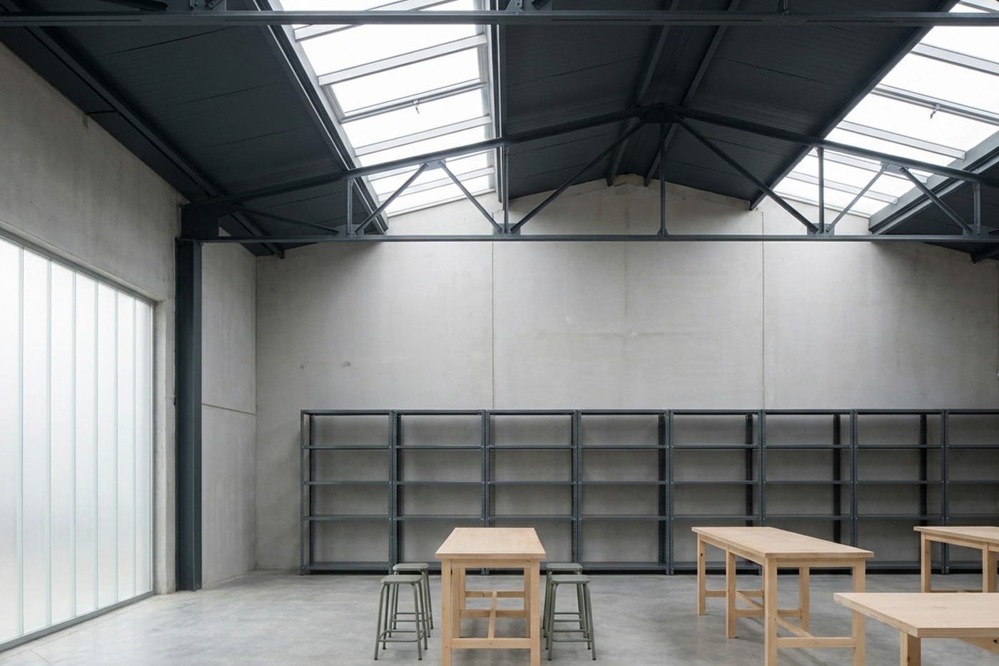 Interior ordenado de un almacén industrial con paredes claras recién pintadas y estructura metálica vista.
